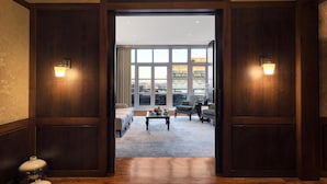 Un vestíbulo de hotel con piso de madera, un ventanal con vista a la ciudad y dos sofás.