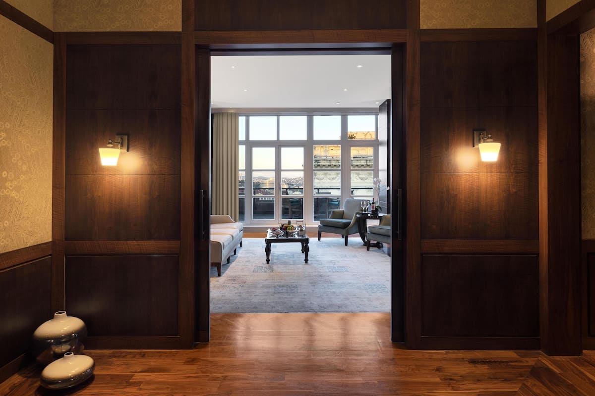 Un vestíbulo de hotel con piso de madera, un ventanal con vista a la ciudad y dos sofás.