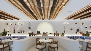 Un interior moderno con una mesa redonda central rodeada de asientos, un techo con vigas de madera y jarrones decorativos en las paredes.