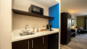 A compact kitchenette with a microwave, sink, and coffee maker.