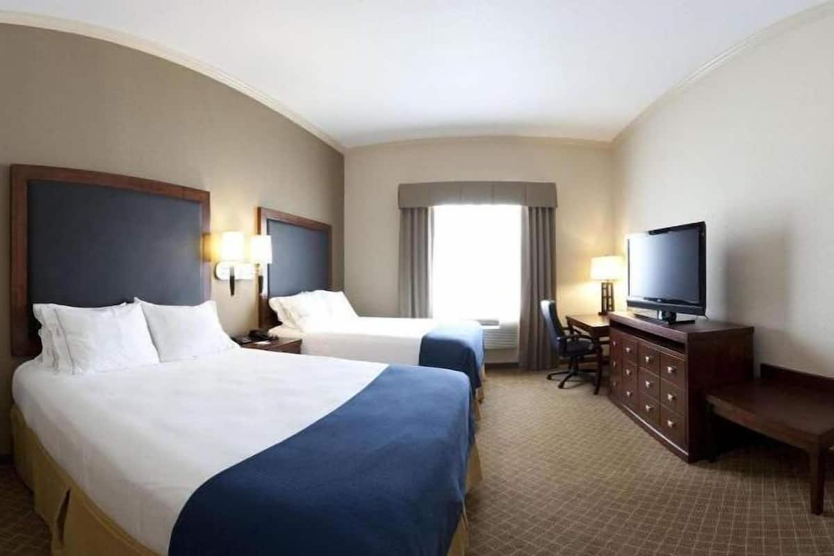 A hotel room with two beds, a television, a desk, and a chair.