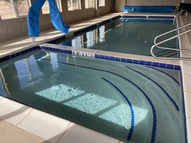 Piscina interior com água cristalina, marcações de profundidade e borda em azulejo.