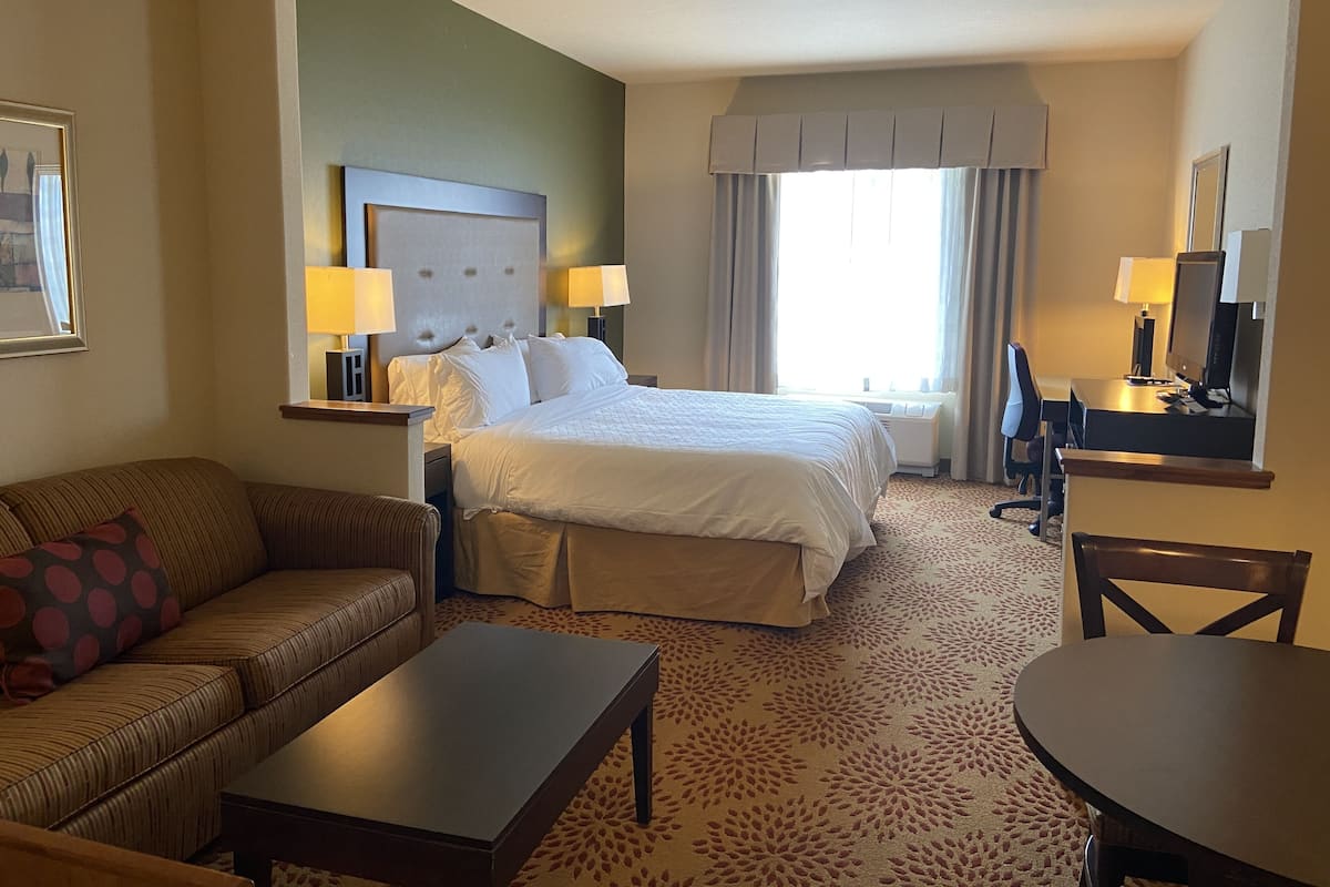 Ein Hotelzimmer mit Bett, Sofa, Schreibtisch und Stuhl.