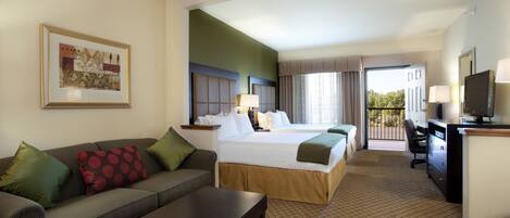 A hotel room with a bed, a sofa, a desk, and a television.