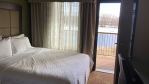A bedroom with a bed, a TV, and a view of a balcony. - Holiday Inn Express & Suites Silt-Rifle by IHG (Silt)
