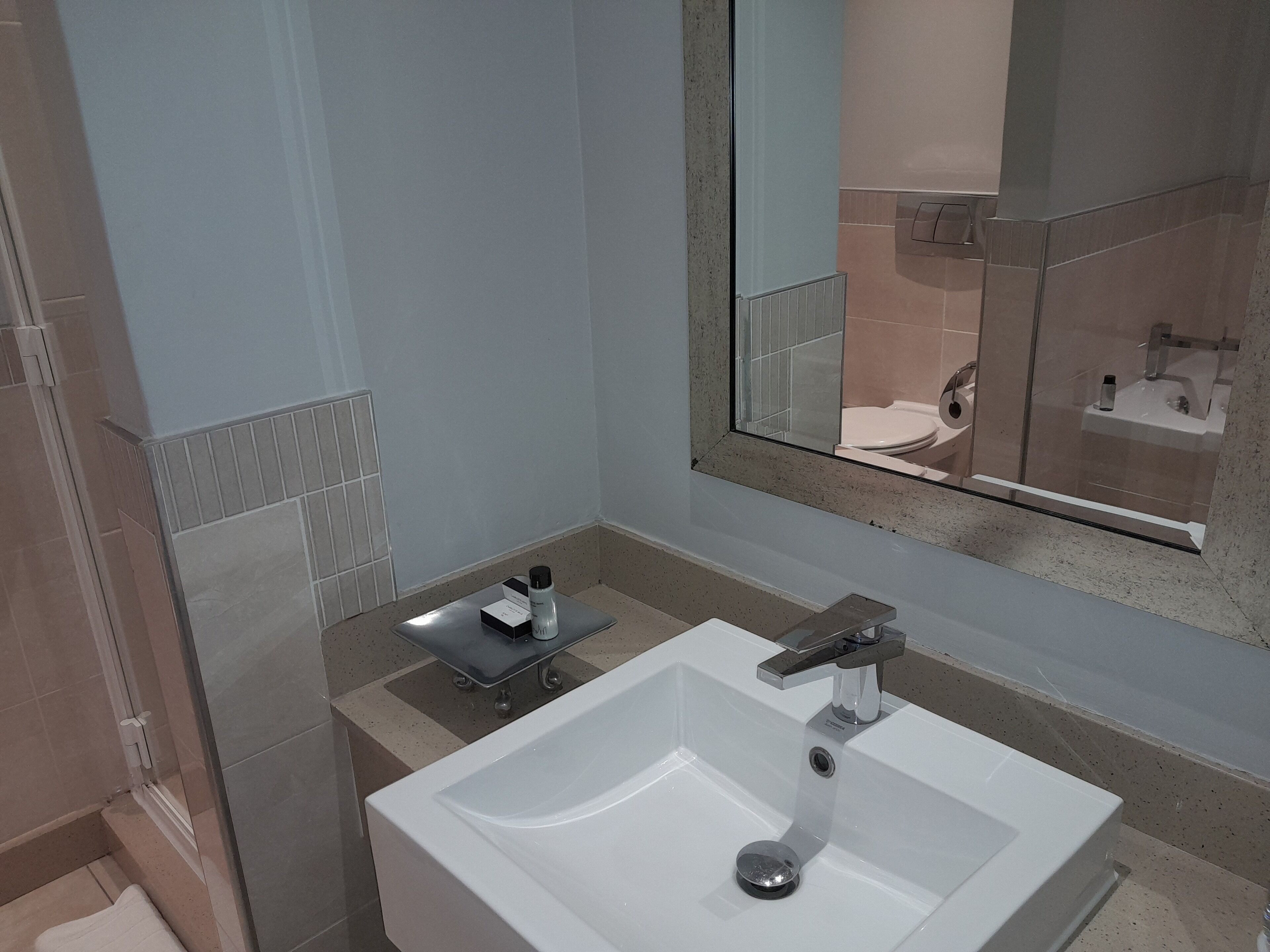 A modern bathroom with a white sink, a mirror, and a shower area.