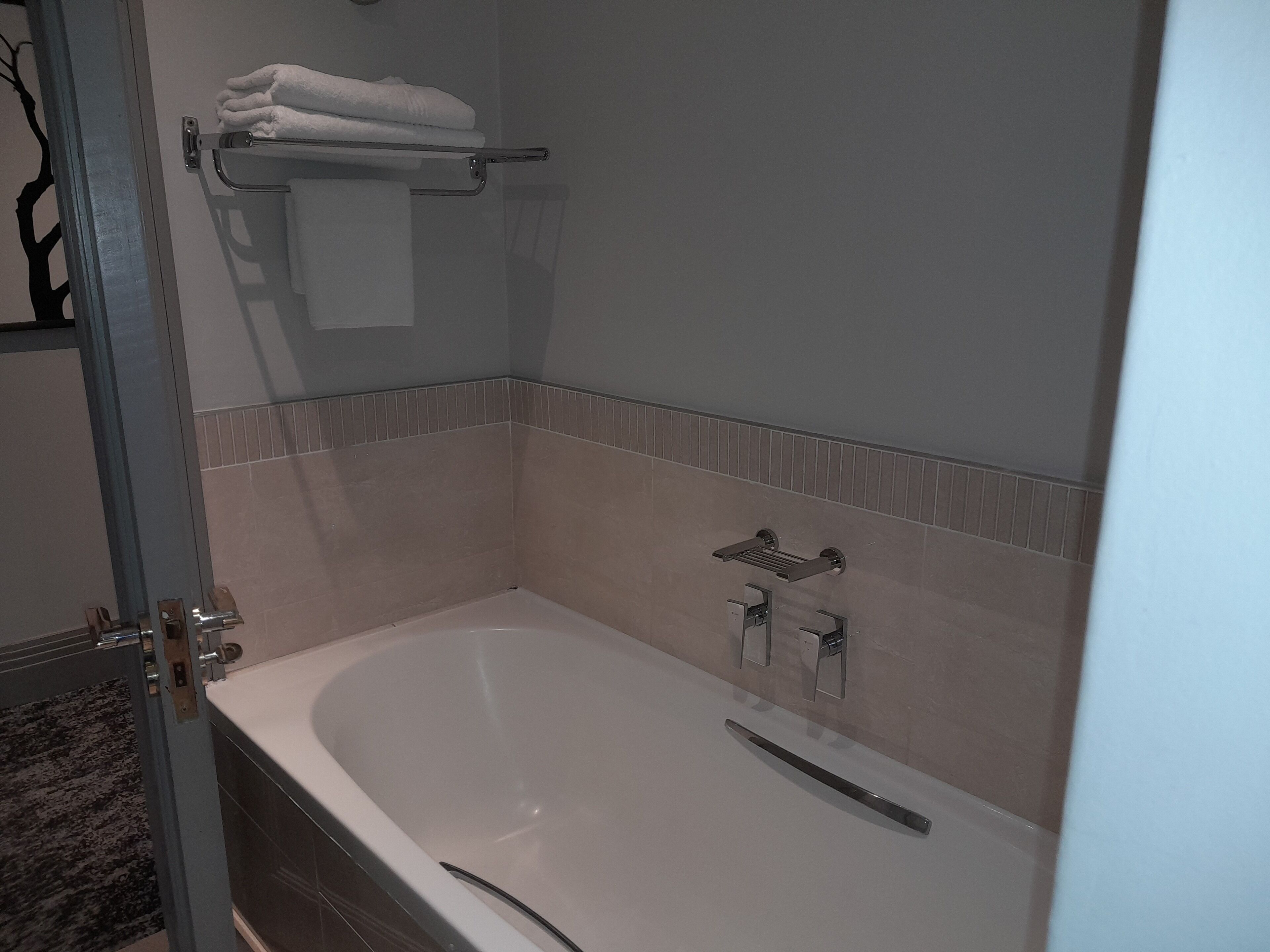 Ein Badezimmer mit einer Badewanne, einem Handtuchhalter mit gefalteten Handtüchern und einer Duscharmatur.