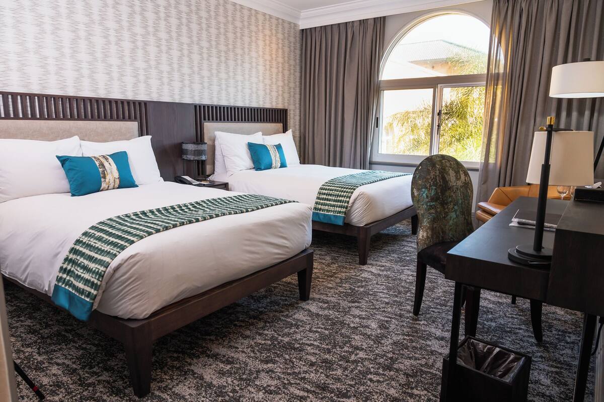 Habitación de hotel con dos camas, un escritorio y una silla.