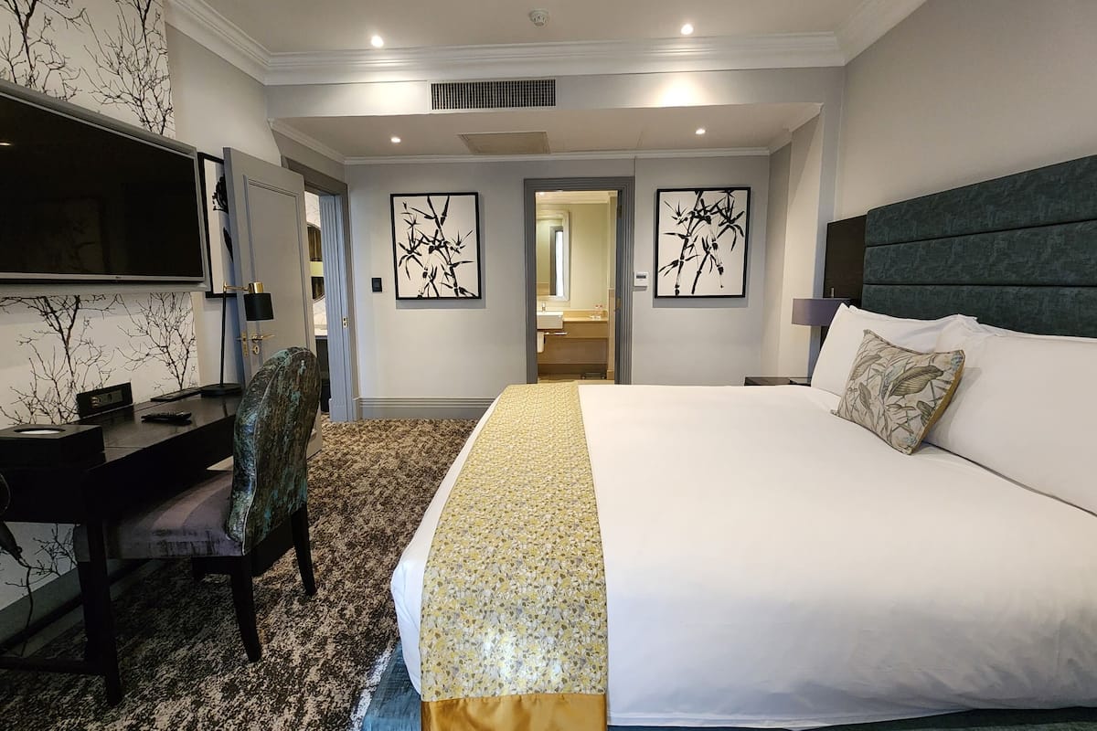 Una habitación de hotel con una cama grande, un escritorio y un televisor.
