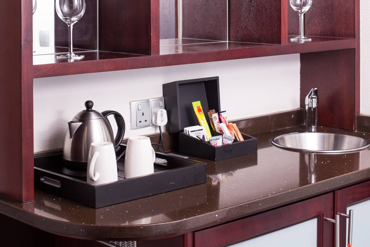 A modern kitchen with dark wood cabinetry, a stainless steel sink, and a glass shelf above the counter.