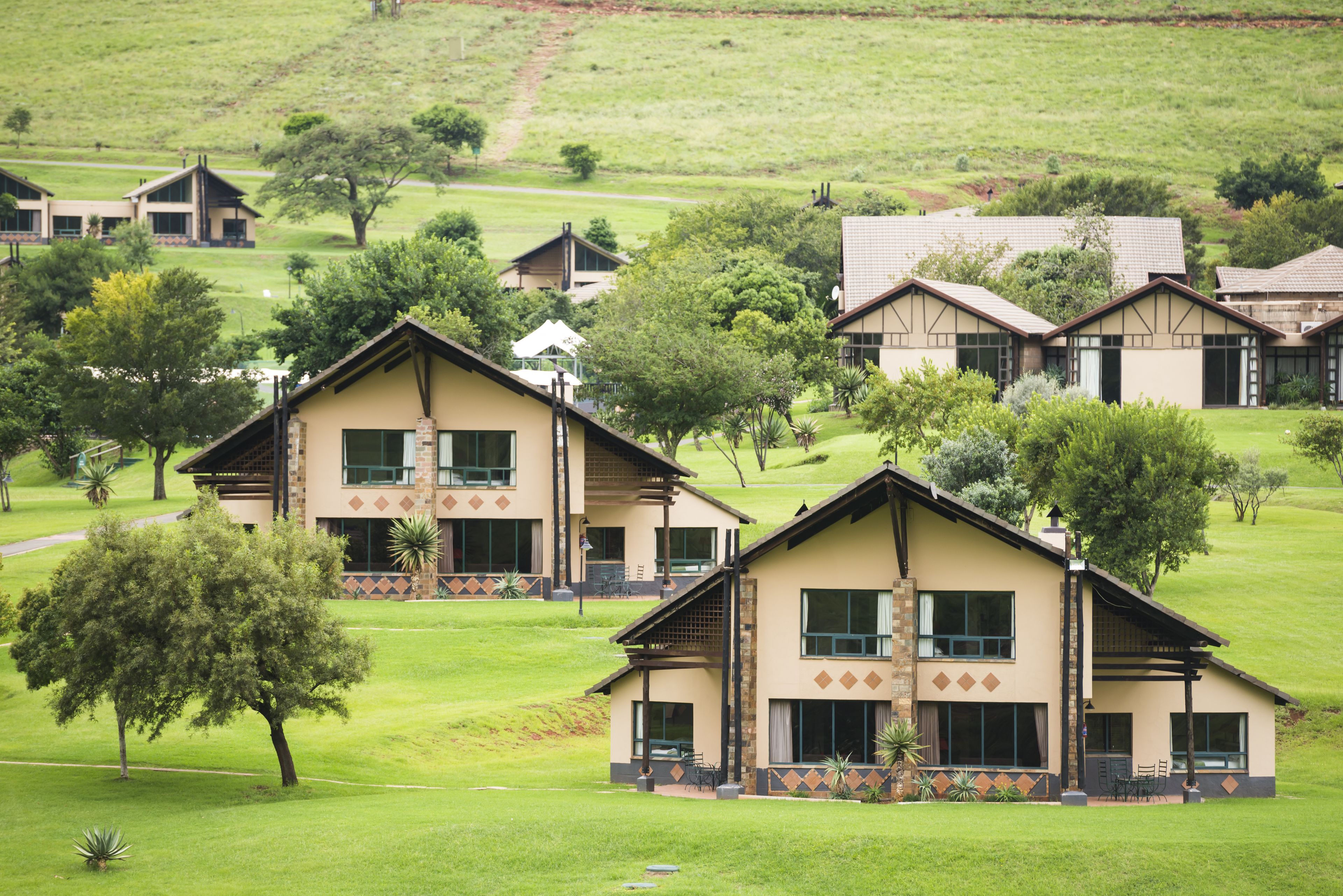 Zona residencial con varias casas de estilo arquitectónico uniforme, rodeada de césped y árboles.