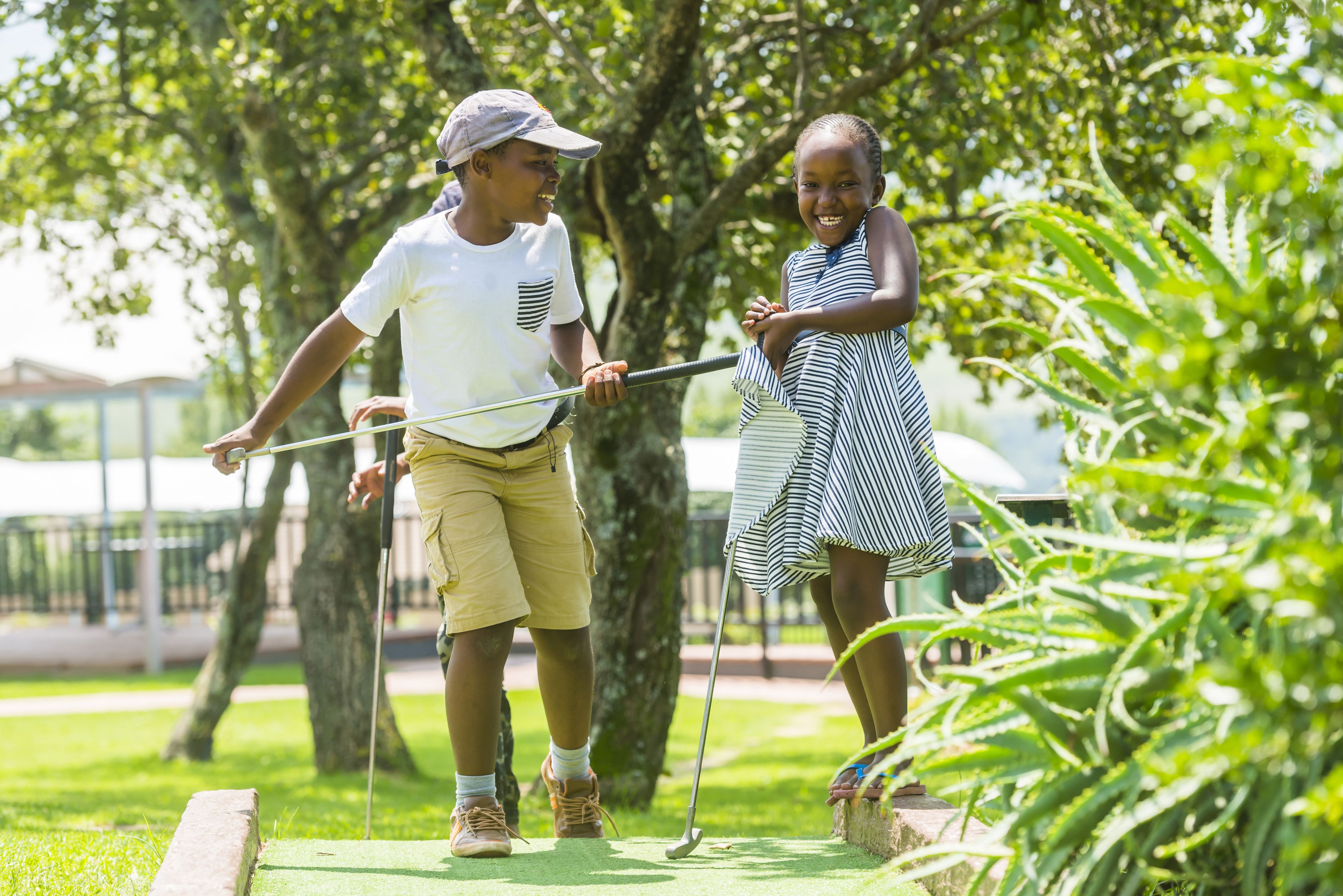 Two people playing golf on a green with trees in the background.