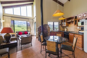 Un salón espacioso con sofá, sillas, una mesa de comedor y una cocina equipada con electrodomésticos modernos.