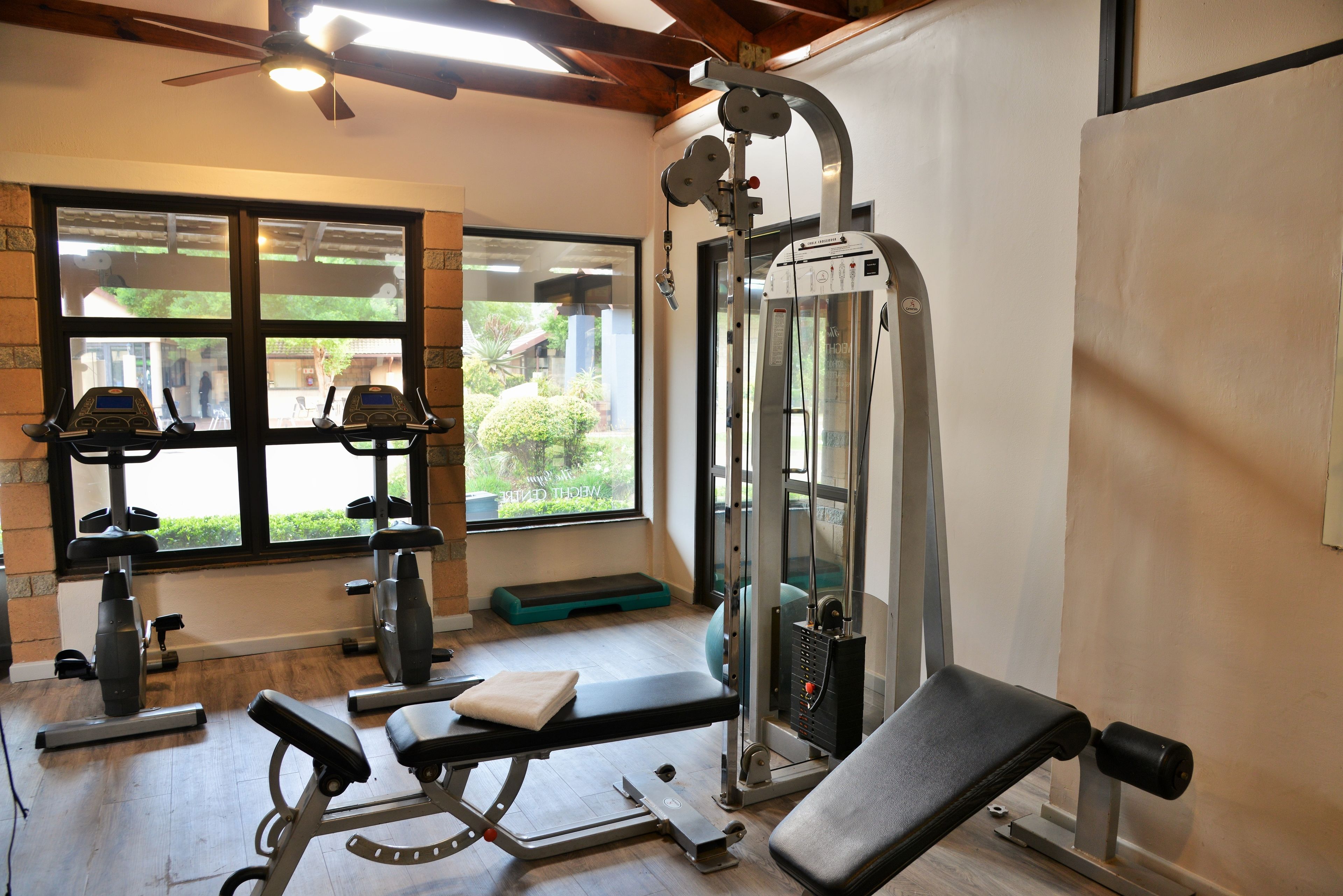 A gym with exercise equipment, a bench, and a window with a view of greenery.