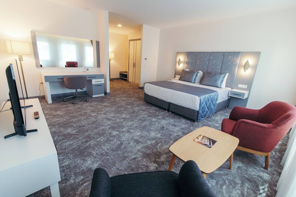 A hotel room with a bed, desk, chair, and a small table.