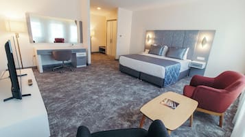 Hotellihuone, jossa on sänky, työpöytä, tuoli ja pieni pöytä.