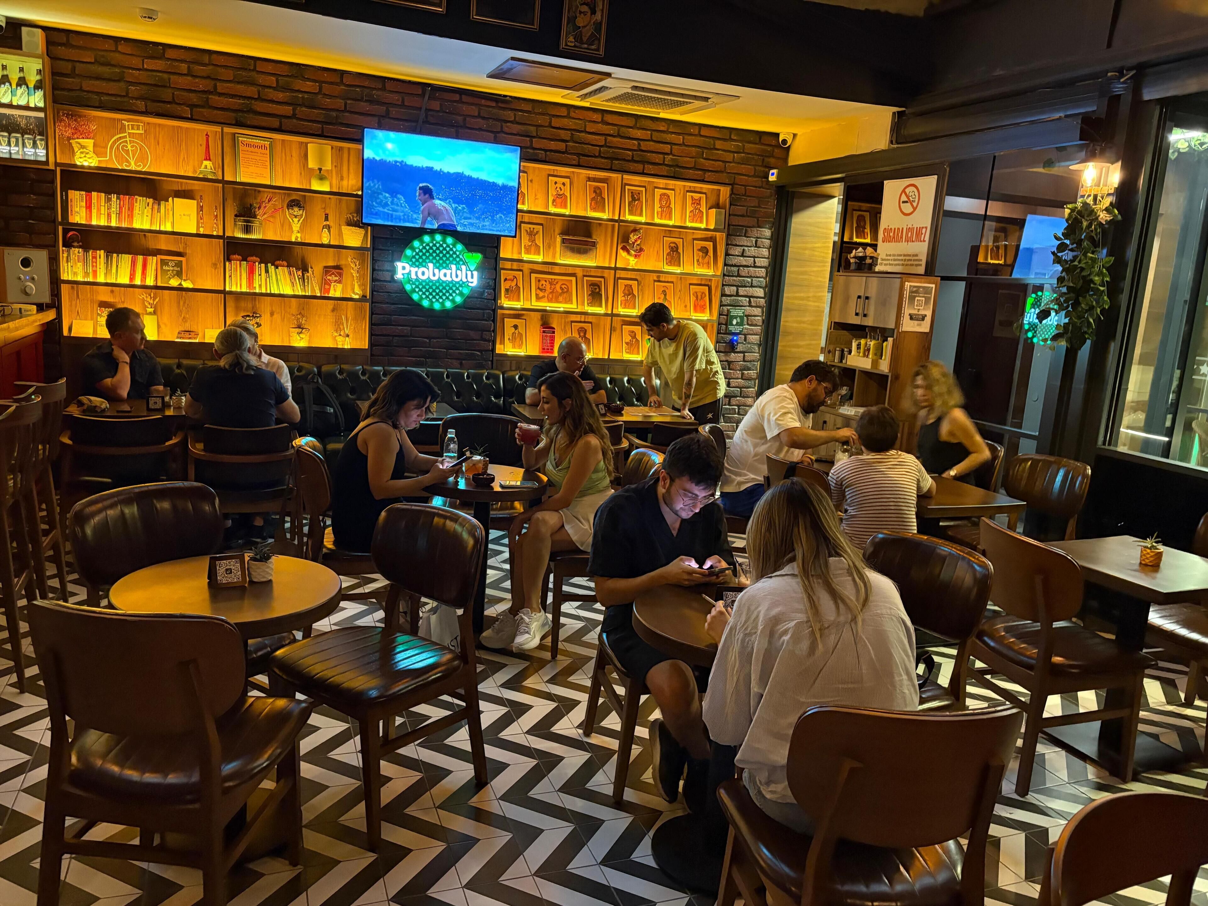 Un restaurante con pared de ladrillo, una pantalla de televisión y una zona de bar con estantes.