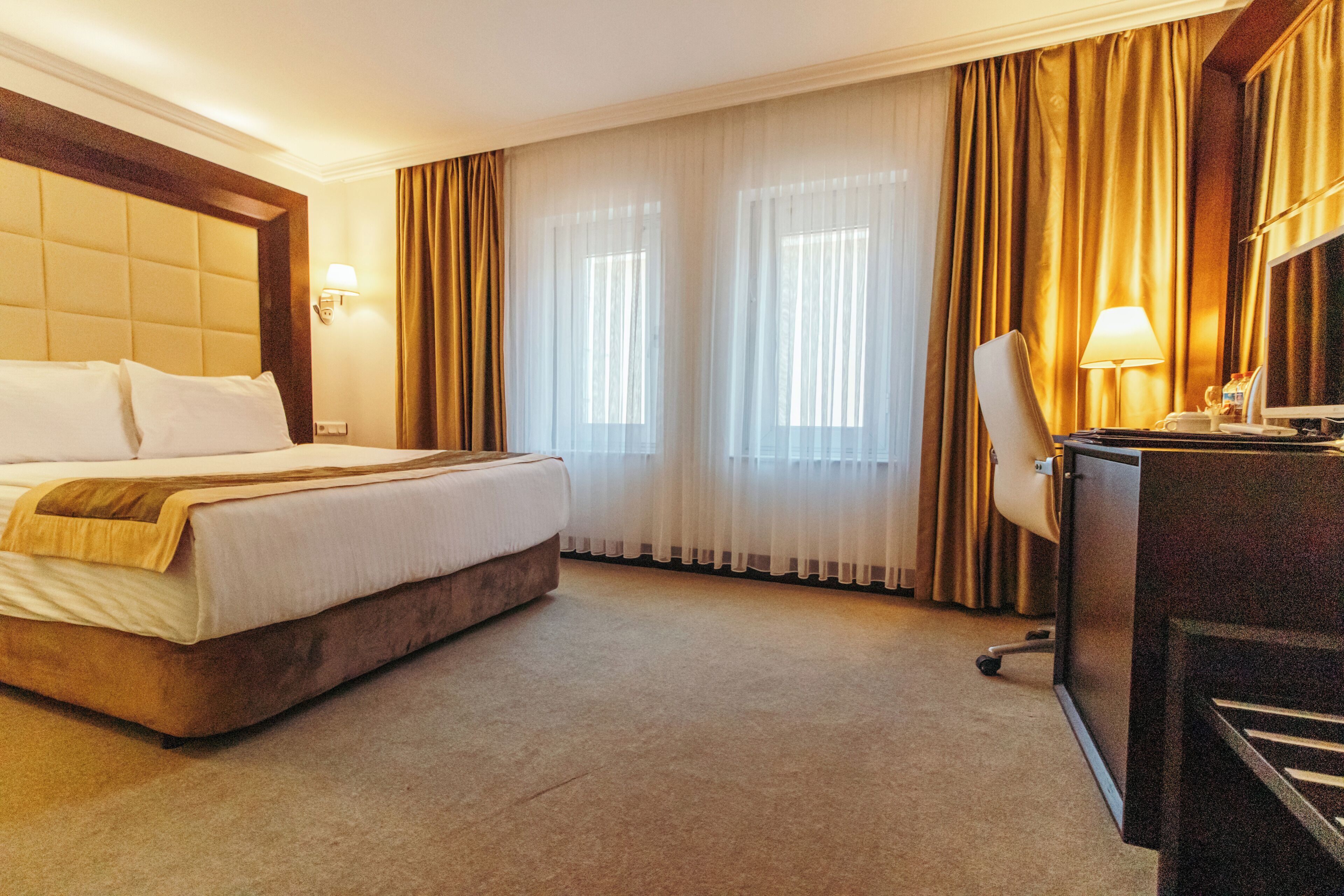 Une chambre d’hôtel avec un grand lit, un bureau avec une chaise et une lampe de bureau.