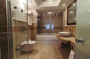 Un baño moderno con ducha envuelta en vidrio, inodoro independiente, bañera y tocador con lavamanos.