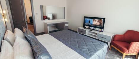 Una habitación de hotel con cama, televisión, escritorio y una silla roja.