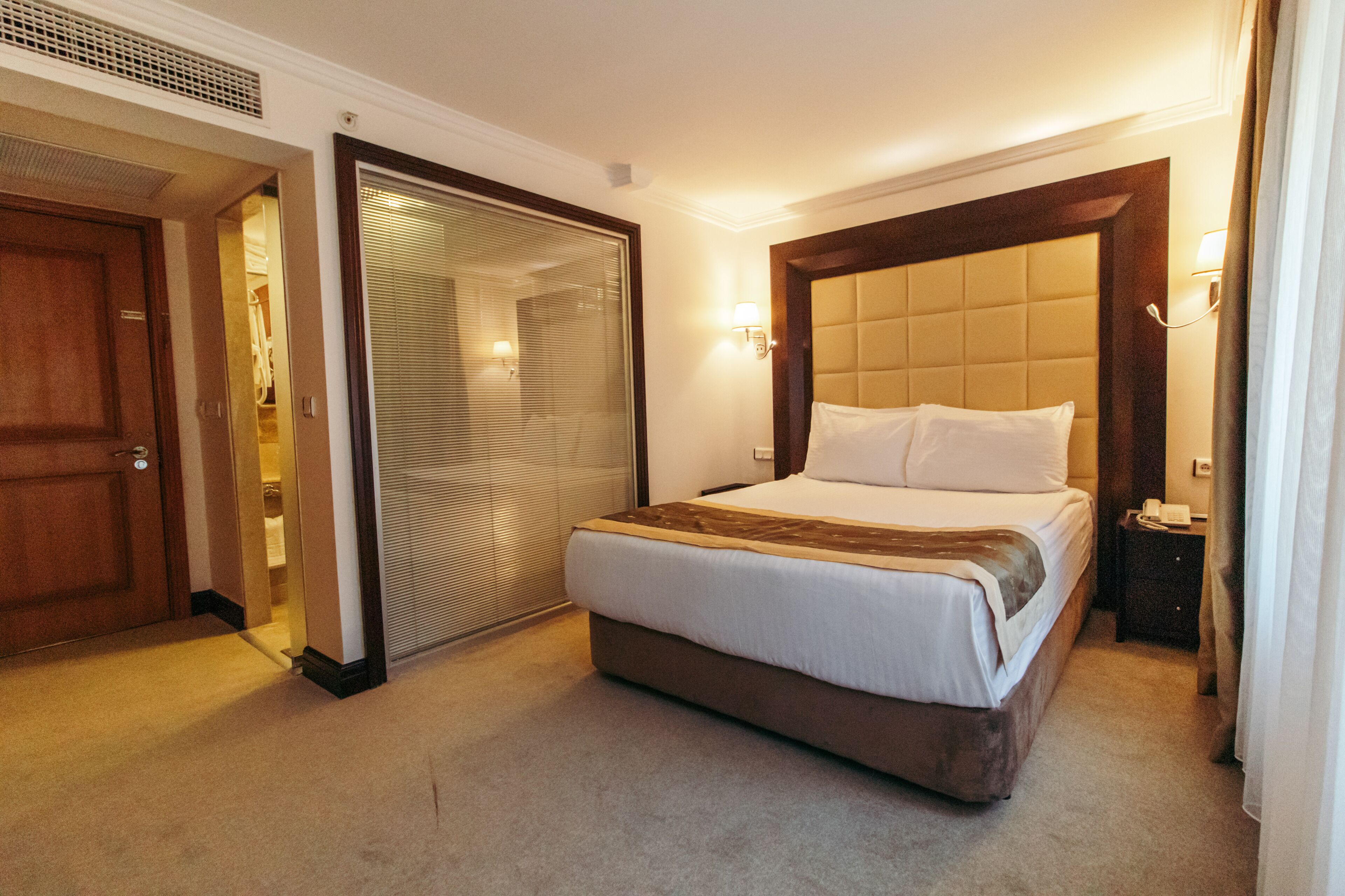 A hotel room with a large bed, a walk-in closet, and a sliding door.