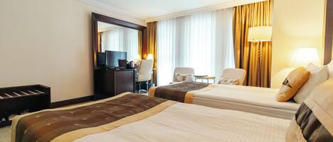 A hotel room with two beds, a desk, a chair, a television, and a mirror.
