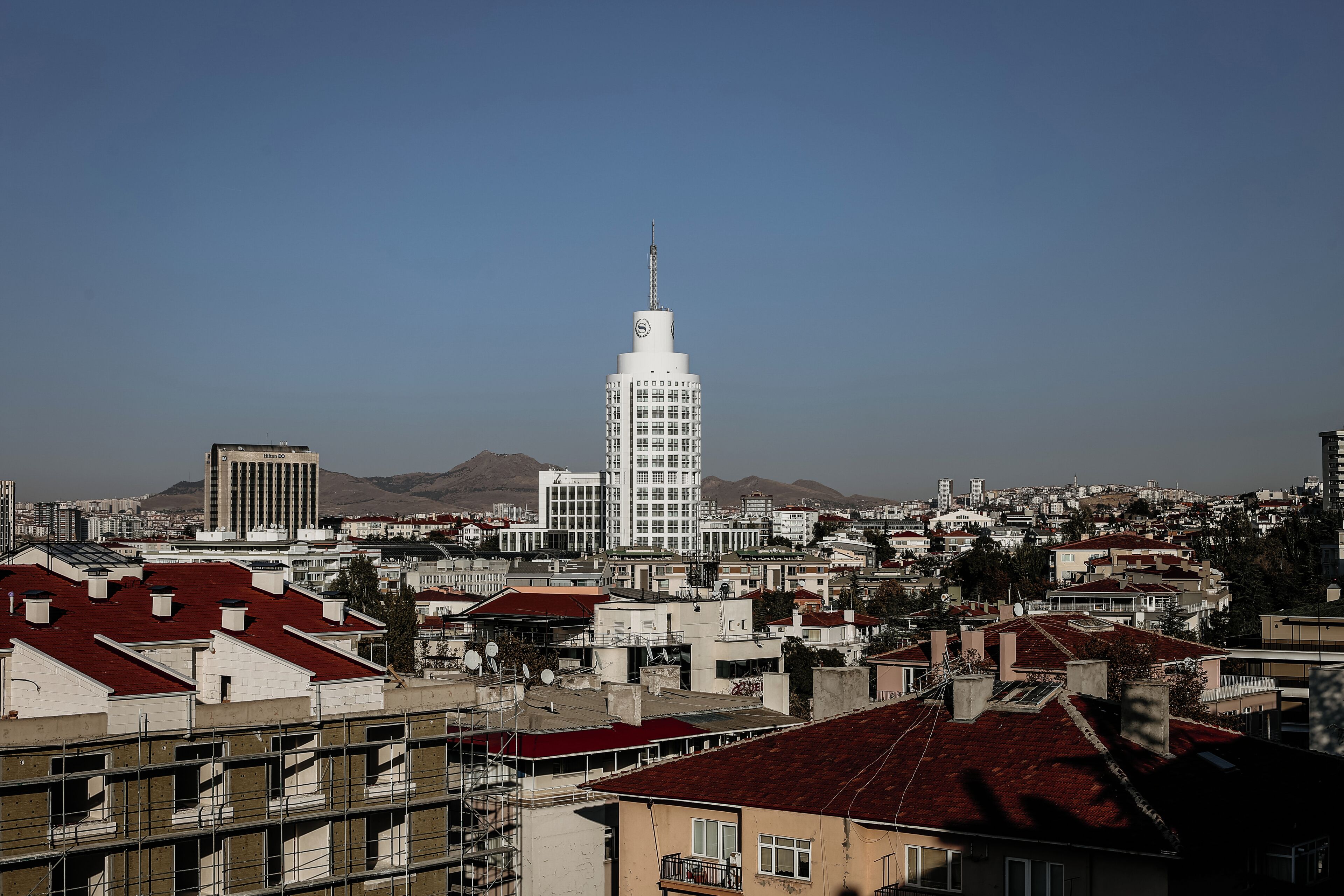 Un paisaje urbano con una torre blanca destacada, rodeada de edificios residenciales con tejados rojos.