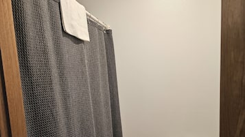 A bathroom with a shower curtain, a toilet, and a wooden door.