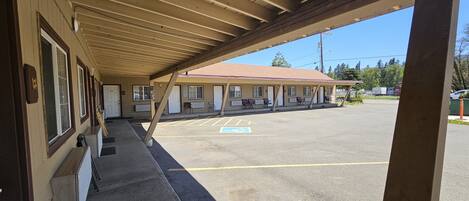 A motel with a covered parking area and a row of rooms with individual entrances.