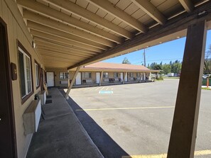 Un motel con estacionamiento techado y una fila de habitaciones con entradas individuales.