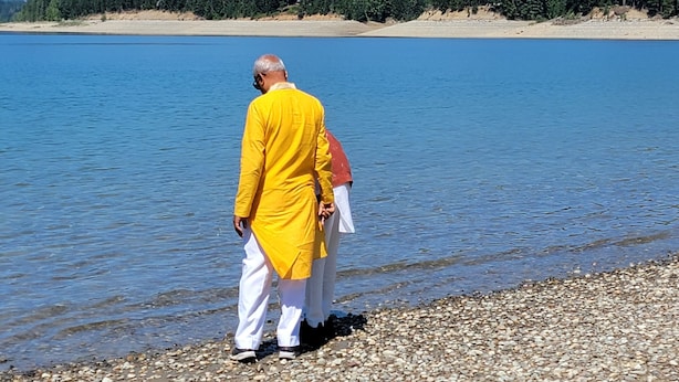 A person in a yellow outfit standing by a lake with mountains in the background. - Cle Elum Travelers Inn (Cle Elum)