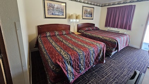 A room with two beds, a window with purple curtains, and two framed pictures on the wall. - Cle Elum Travelers Inn (Cle Elum)