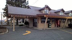 A building with a covered entrance, a Coca-Cola vending machine, and a sign indicating it is open to the public. - Cle Elum Travelers Inn (Cle Elum)