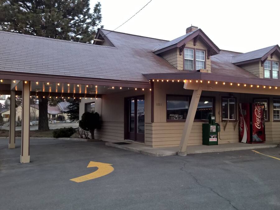 A building with a covered entrance, a Coca-Cola vending machine, and a sign indicating it is open to the public.