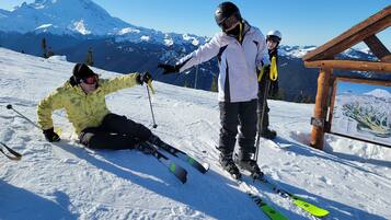 A snowy ski slope with a wooden structure, likely a lodge or information board, and a mountain in the background.