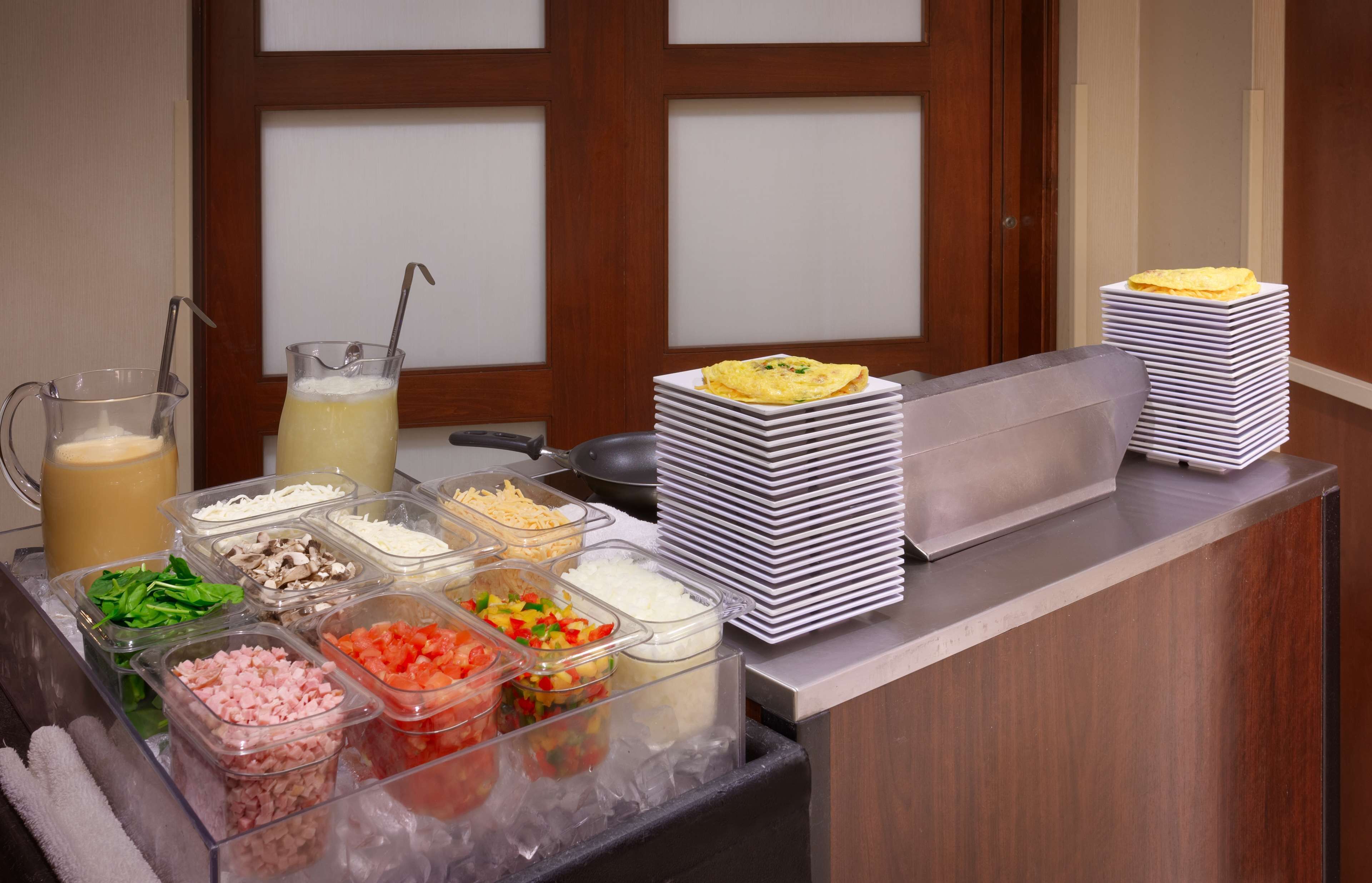 A buffet setup with various food containers and a stack of plates.