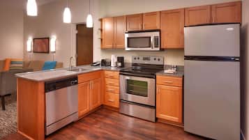 A modern kitchen with wooden cabinets, stainless steel appliances, and a built-in dishwasher.
