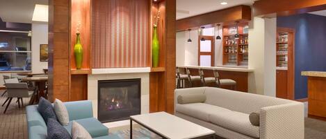 A modern living room with a fireplace, two sofas, a coffee table, and a bookshelf.