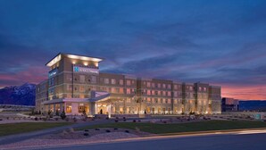 Een meerlaags hotel met een modern ontwerp, met een opvallende entree en een aangelegde voortuin.