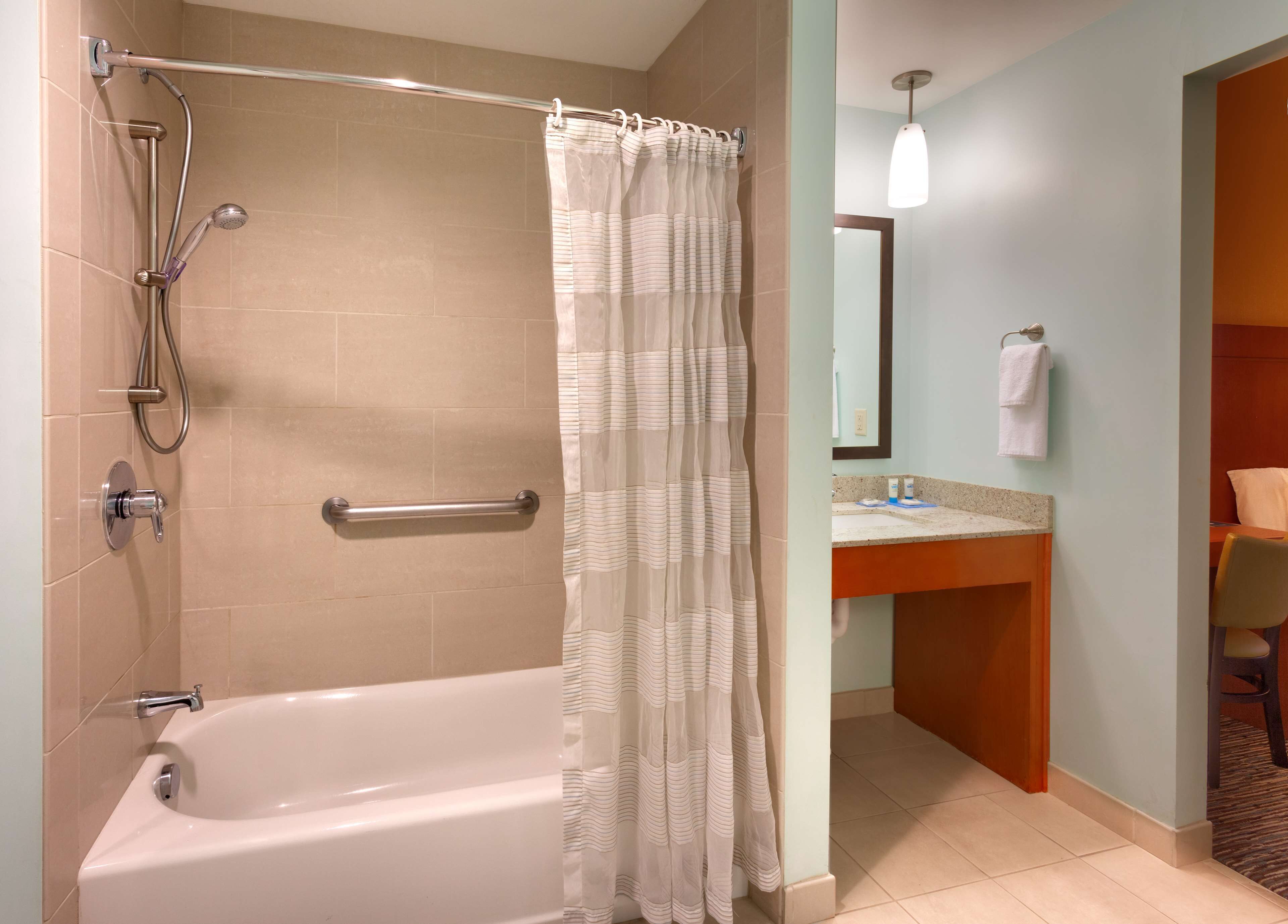 A modern bathroom with a bathtub, shower, and a vanity with a mirror.