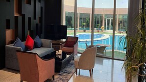Una sala moderna con un televisor grande, asientos cómodos y vistas a una piscina.