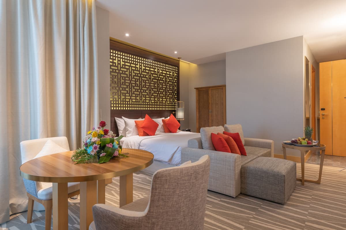 Ein Hotelzimmer mit einem Bett, zwei Sofas, einem Tisch und einem kleinen Beistelltisch.