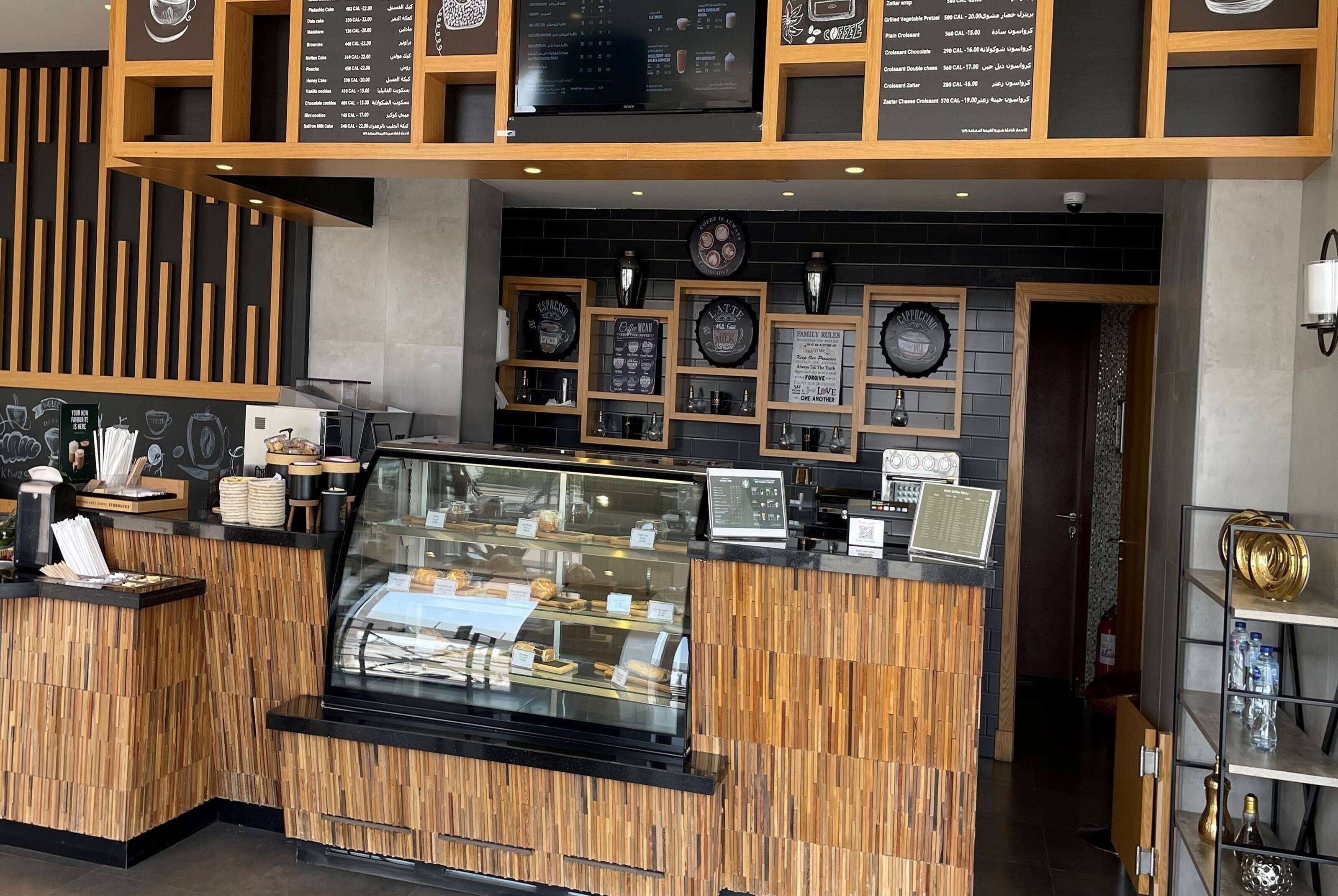A coffee shop interior with a wooden counter, menu boards, and decorative wall elements.