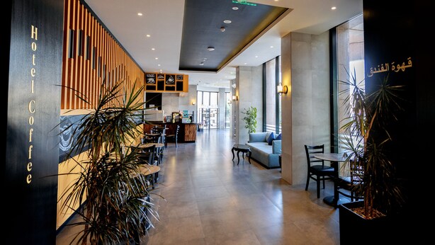 Un moderno vestíbulo de hotel con una barra de café, zona de estar y un mostrador de recepción.