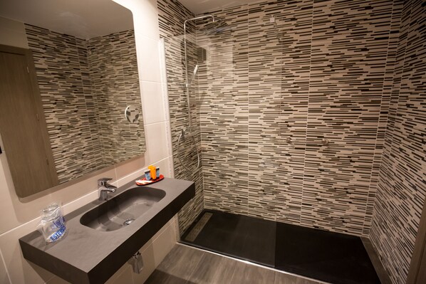 A modern bathroom with a black sink, a mirror, and a shower area.