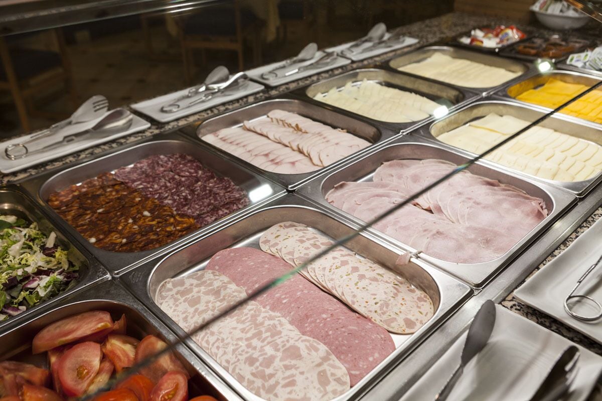 A buffet with various meats and cheeses.
