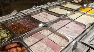 A buffet with various meats and cheeses.