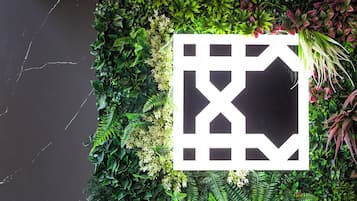 A wall with a geometric pattern and lush green foliage.