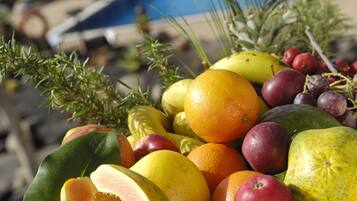 Un panier de fruits rempli de différentes sortes de fruits, avec une piscine en arrière-plan.