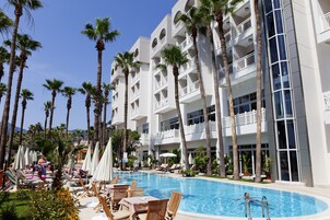 Una piscina al aire libre, sombrillas, sillones reclinables de piscina
